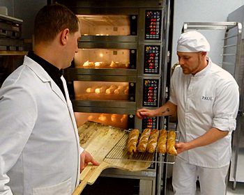 Thomas Crombez and Nicolas Gautier remove baguetts from oven at Masion Paul in Somerville